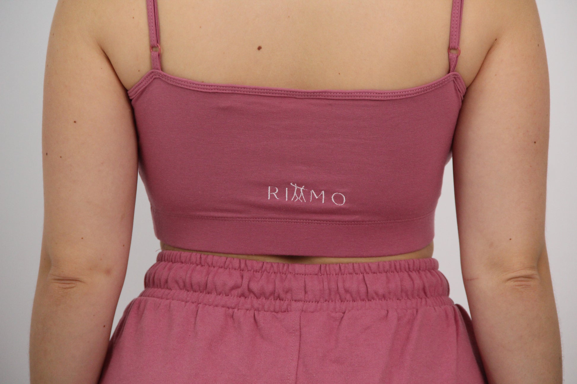 Parte trasera del conjunto urbano rosa de Rittmo con logo. Contraste de elegancia y frescura para bailar bachata con libertad y actitud